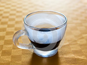 Iced cup of espresso on a table with orange tablecloth