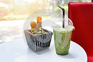 Iced drinks green tea smoothie - Matcha green tea with milk on plastic glass on the wooden table and nature green background