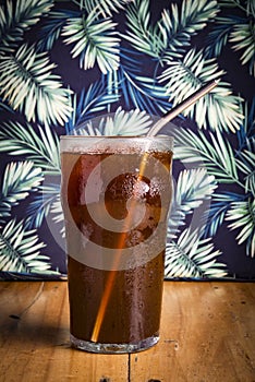 iced espreso coffee drink with tropical green leaf as background