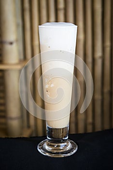 Iced frappe coffee on a wood table with a bamboo background