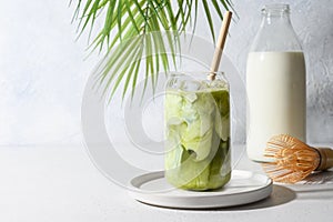 Iced Green matcha tea mixed with ice cube and milk in latte glass on white