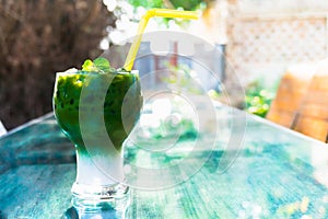 Iced green tea latte in glass on table at garden