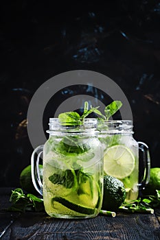 Iced green tea with lime and mint in glass jars, dark background