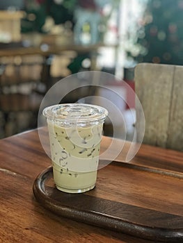 Iced green tea in plastic cup on wooden table in coffee shop