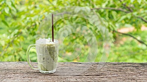 Iced green tea on a wooden table and green nature background