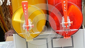 Iced juice machine juicer containing row of red and yellow slushes being prepared in slush machines on the street food