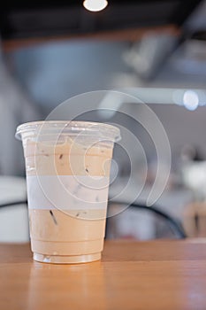 Iced latte coffee in plastic takeaway glass on wood table