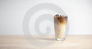 Iced latte coffee on wooden table, white background.