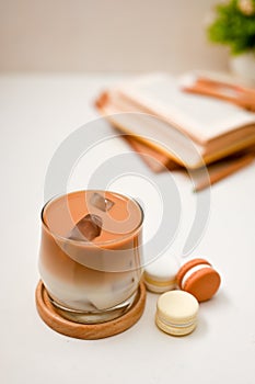 Iced latte. Cold brew coffee drink with ice and macarons on white table background