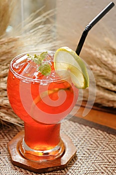 Iced lemon tea with lime and mint decoration on wooden and cereal background - Soft focus