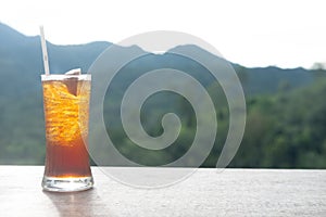 Iced lemon tea in long glass on the green nature background