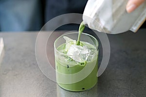 Iced matcha latte - A glass of green tea with milk on the table.