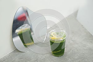 Iced matcha lemon soda - A plastic glass of green tea mixed with honey lemon soda on the table