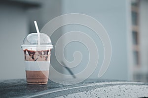 Iced mocha coffee on front roof of car after raining