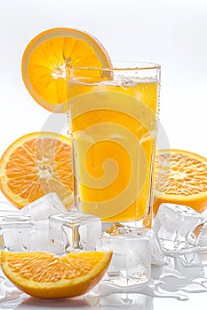 Iced orange juice in a glass with many condensation droplets, surrounded by ice cubes and slices of oranges