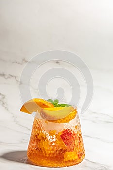 Iced peach cocktail with peach slices, summer Peach cocktail, homemade peach lemonade with ice cubes, and mint in glass