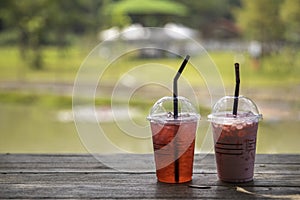 Iced Pink milk, Thai style iced sweet milk with cider syrup and iced red water  on the wooden table in the peaceful coffee shop