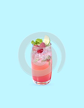 Iced red raspberry punch cocktail with lime in glass on blue background. summer drink