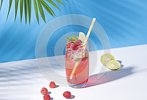 Iced red raspberry punch cocktail with lime in glass on color background. summer drink