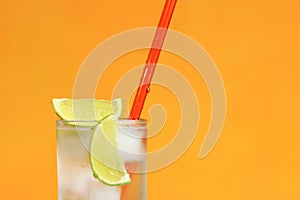 Iced tea with ice and lime on an orange background. Summer cocktail