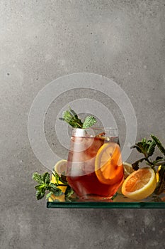 Iced tea with lemon and mint on the background of the grey concrete wall