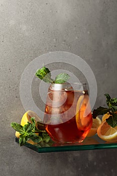 Iced tea with lemon and mint on the background of the grey concrete wall