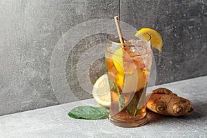 Iced tea with mint, ginger, and lemon on a grey background
