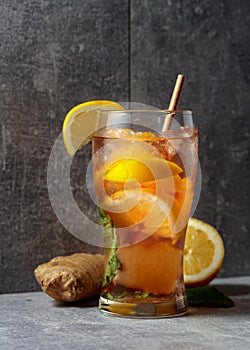 Iced tea with mint, ginger, and lemon on a grey background