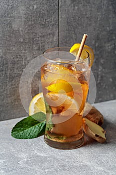 Iced tea with mint, ginger, and lemon on a grey background