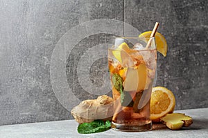 Iced tea with mint, ginger, and lemon on a grey background