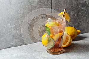 Iced tea with mint and lemon on a grey background