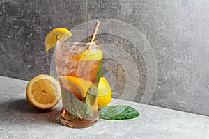 Iced tea with mint and lemon on a grey background