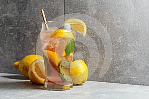 Iced tea with mint and lemon on a grey background