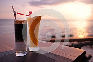 Iced Vietnamese coffee and orange juice on table, at bar restaurant balcony, sea facing, sunset in background. Beautiful relaxing