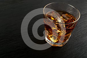 Iced Whiskey Glass on Natural Black Stone Background