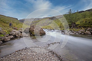 Iceland, a big rock and little rocks in a fast flowing river, with a fabulous blue sky in autumn colours