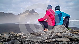 Iceland - couple sitting at the rock, looking at the mountains