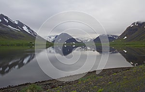 Iceland darl cloudy rainy day fjord view with green and blue hills.