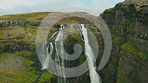 Iceland fly through Aerial of a Glymur Waterfall with a Girl sitting near cliff.