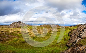 Iceland landscape with orange lava hill and green grass valley way to volcano