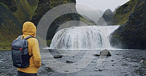 Iceland, man with backpack enjoying Stjornarfoss waterfall near Kirkjubaejarklaustur