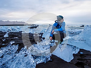 Iceland - Man at the black sand beach with ice bergs on the shore