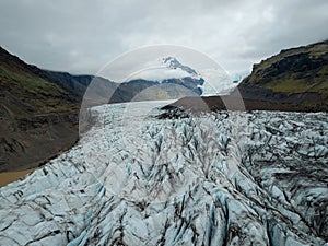 Icelandic landscape of a glacier tongue spurting off ice cap, drone shot