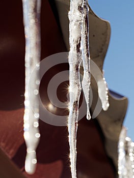 An icicle illuminated by sunlight against the roof