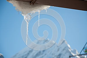 Icicle from rooftop with mountain peak in the back