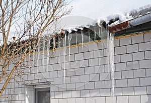 Icicles damage roof and gutter. Ice Damming. photo