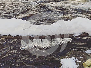 Icicles freeze on the branch above river