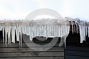 Icicles hang down from the roof of the house in winter. Danger to humans