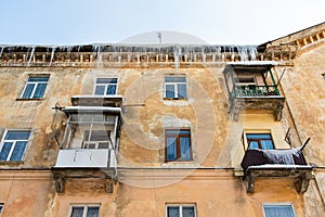 Icicles hang from roof of building. Danger for passers, threat of death and injury from icicles. Theme the winter risks