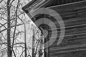 Icicles hang from the roof of a wooden house on a warm, cloudy day